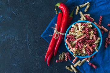  healthy colored vegetarian pasta on a dark blue background with spices and pepper