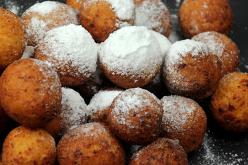 Small balls of freshly baked homemade cottage cheese with sugar powder on black background. Freshly made donuts from cottage cheese with powdered sugar