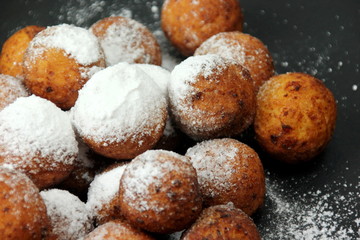 Small balls of freshly baked homemade cottage cheese with sugar powder on black background. Freshly made donuts from cottage cheese with powdered sugar