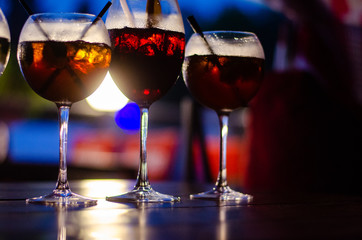 Beautiful row line of different colored alcohol cocktails on a party, martini, vodka,and others on decorated catering bouquet table on open air event, picture with beautiful bokeh