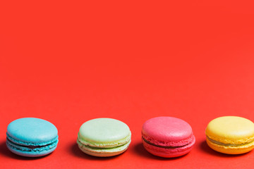 Sweet and colourful french macaroons or macaron on red background with copy space.
