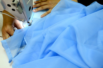 The seamstress sews on a sewing machine, fulfills the order. Scribbles a blue cloth. Sewing...