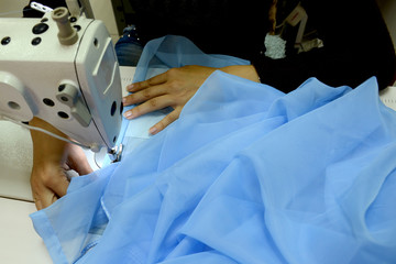 The seamstress sews on a sewing machine, fulfills the order. Scribbles a blue cloth. Sewing...