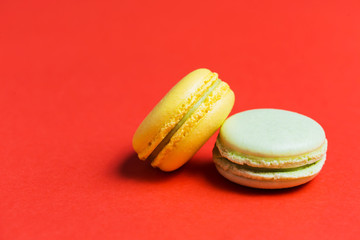 Close up of two green and yellow French macaroons on a red background