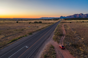 Top view of highway and red car on the road, close to Colorado city. Cottonwood point. Sunset sky, mountains. Arizona, USA