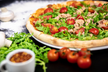 Declicious pizza with ingredients on the side, backed in traditional wooden oven.