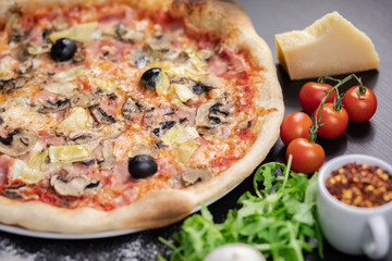 Declicious pizza with ingredients on the side, backed in traditional wooden oven.