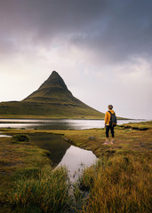 Jonge wandelaar met een rugzak kijkt naar de berg Kirkjufell in IJsland