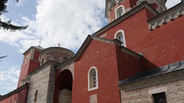 Red facade of Serbian Zica monastery against blue sky 4K tilting footage