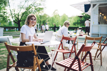 Optimistic woman working with laptop in cafe