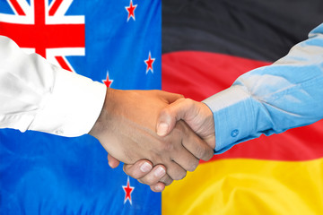 Handshake on New Zealand and Germany flag background.