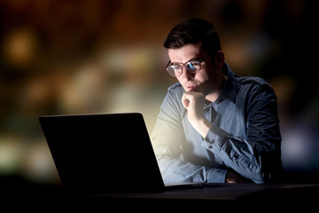 Young handsome businessman working late at night in the office