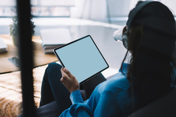 Faceless female surfing tablet while drinking coffee at modern home