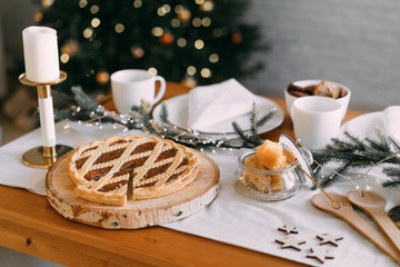 Cristmas decor kitchen table witkh pie, candles, fir, lights. Winter Holidays. Christmas background concept.