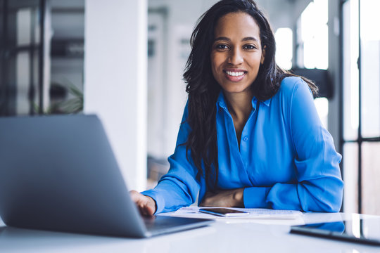 Confident ethnic businesswoman using laptop at work