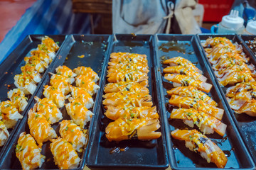 Rows of japanese sushi food. Maki ands rolls with tuna, salmon, shrimp, crab and avocado. Top view of assorted sushi in black plastic container being sale at market. Selective focus.