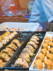 Rows of japanese sushi food. Maki ands rolls with tuna, salmon, shrimp, crab and avocado. Top view of assorted sushi in black plastic container being sale at market. Selective focus.