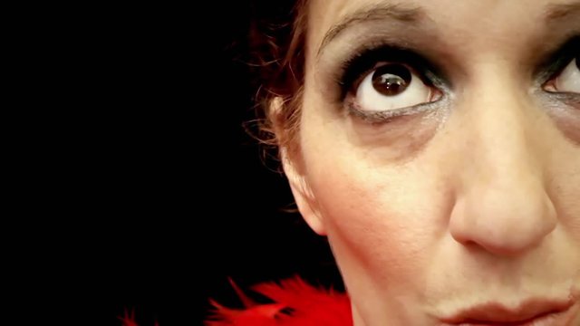 A beautiful lady, becoming angry, getting bothered by someone near her. Front extreme close-up shot, detail of half her face, black background.