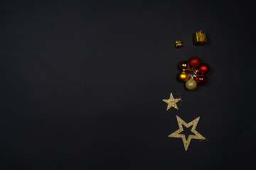 Christmas ornaments (Christmas baubles, stars and little presents) on black background