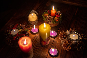 Many burning candles in the dark on a wooden table.