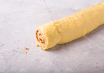 Beautiful fresh cinnamon rolls. The cooking process, cut the thread roll. Fresh fragrant pastries. Raw dough for buns. Lifehack