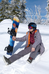 Fototapeta na wymiar Young snowboarder in the mountains on top. Active rest on a snowboard.