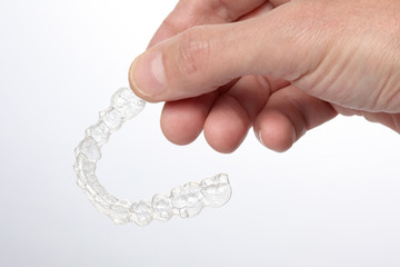 man's hand  hold a teeth brace aligner  isolated on white background with copy space for your text