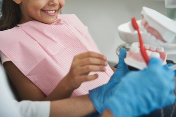 Obraz na płótnie Canvas Smiling cute girl visiting her professional dentist