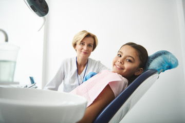 Obraz premium Positive little girl sitting in the dentists chair during the check up