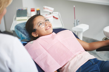 Joyful little girl visiting her professional dentist