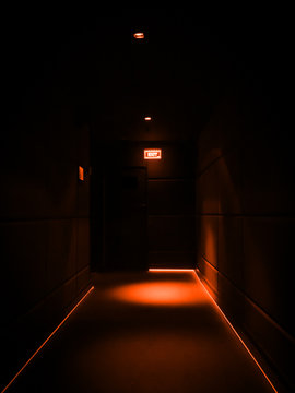 Empty dark corridor illuminated with orange lights in a building