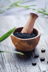 Skin care. Ingredients for mask and scrub with activated charcoal powder on dark wooden table, copy space.
