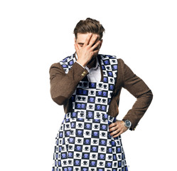 Young attractive man in a businessman suit and home apron for cleaning, in desperation covered his face with his hand. Isolated on a white background.