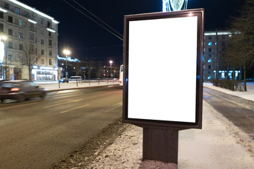 Vertical advertising city billboard format in winter in the city at night. Ad design MOCKUP with white field.