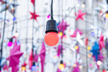 Red light bulb hanging in the middle with a lot of stars on background