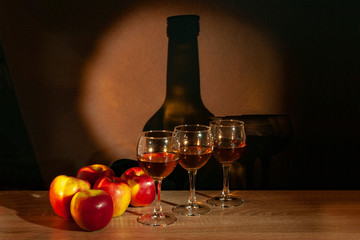 Three glasses with calvados and apples on the table on the background of the bottle - obrazy, fototapety, plakaty