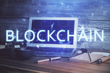 Multi exposure of blockchain theme hologram and table with computer background. Concept of bitcoin crypto currency.