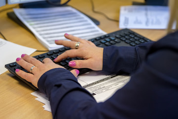 London, England, 28/01/2019 Colour Color image of young woman call girl in an administrative role admin work for corporate company in modern office typing on the computer keyboard close up on hands.