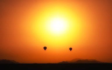2 balloons in front of the sunset in the dessert