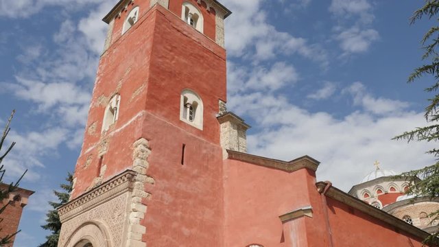 Red facade of old Serbian orthodox monastery Zica 4K tilting video