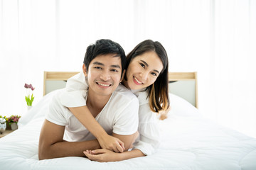 Obraz na płótnie Canvas Funny and romantic Asian couple' portrait in bedroom with natural light from window, concept of relationship between husband and wife and being a family.