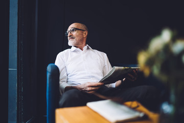 Senior man with newspaper sitting on chair