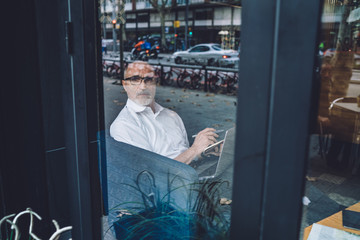 Mature man looking through window at street