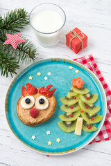 Christmas pancake in a shape of reindeer made of fresh fruits and berries and kiwi christmas tree. Healthy food for kids ideas. Top view