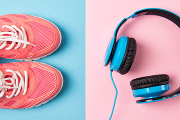 Bright pink sneakers and blue headphones on blue and pink background, top view