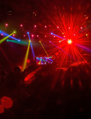 Fototapeta na wymiar ray of red light flare at a night music festival with crowd of people with phone raised 