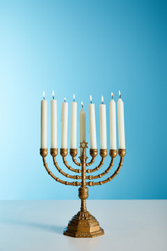 Burning Candles In Menorah On Blue Background