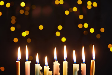 Glowing candles on black background with bokeh lights on Hanukkah