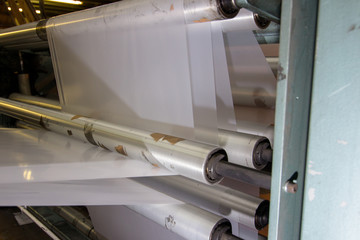 imagery White spool of plastic packaging sheet heavy duty for industrial use outdoors. wrapped around a metal pole ready to feed into a machine for cutting into shape or printing logos.