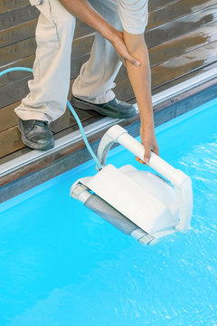African hand Pool cleaner during his work. Cleaning robot for cleaning the botton of swimming pools. Automatic pool cleaners